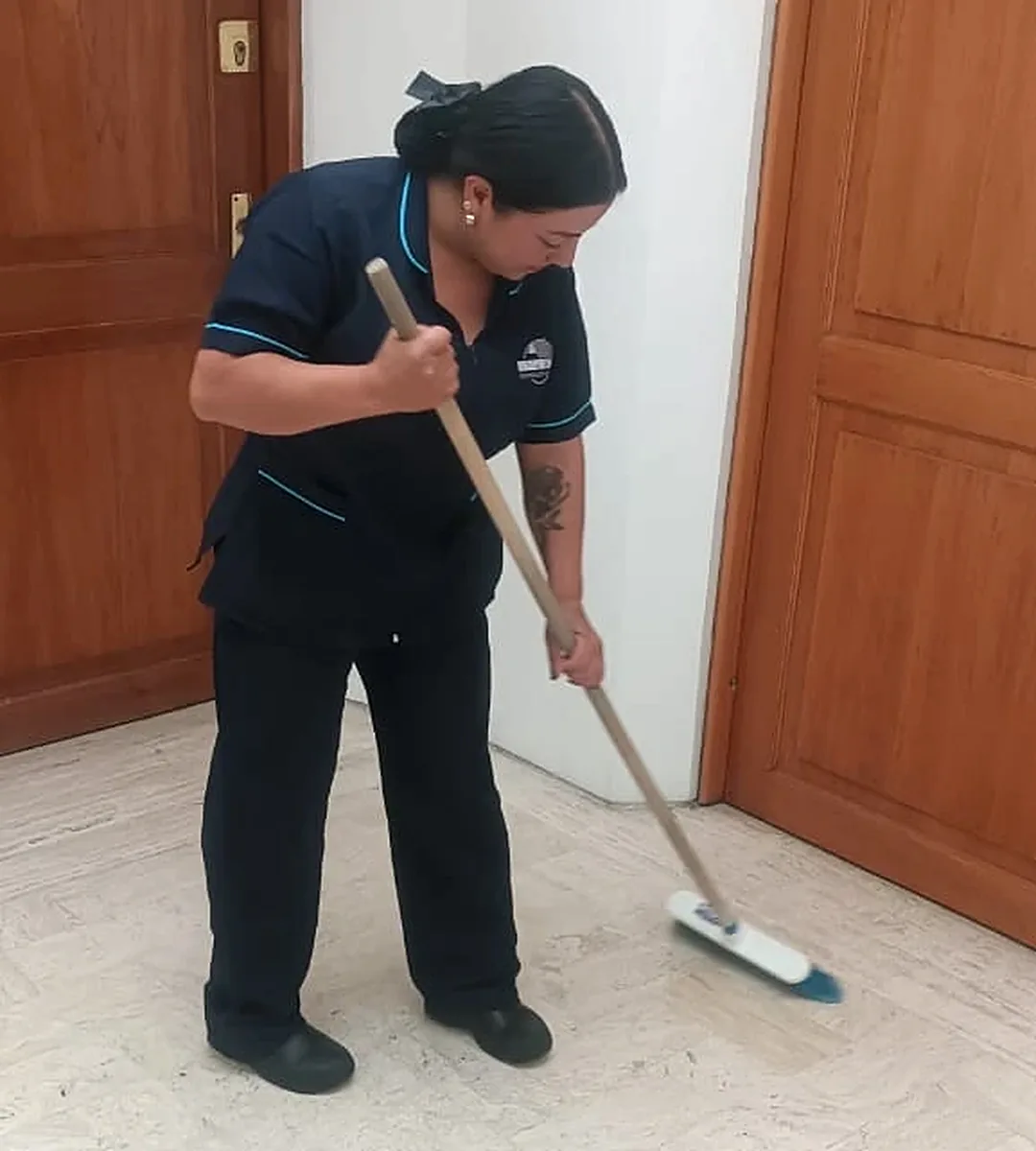 Operaria de servicios generales de PROPH S.A.S. barriendo una zona común